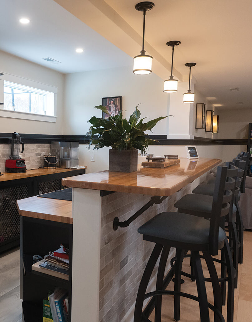 Basement bar detail with wood countertop and seating in Dover NH by Woodstone Homes